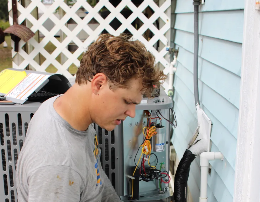 Big Air technician checking refrigerant and electrical readings on an AC condenser in Fort Myers